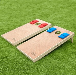 To træbord til shuffleboard med røde og blå skiver på en græsplæne.