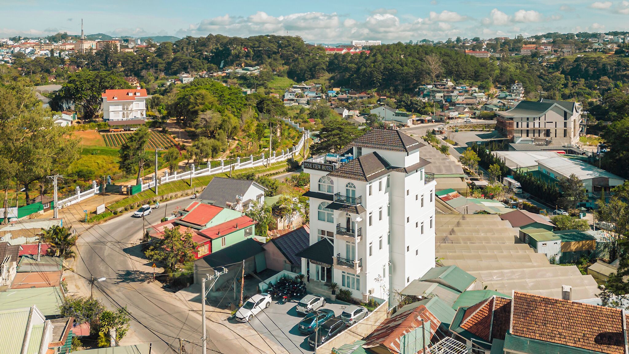 Un hotel con una torre destacada, rodeado de edificios residenciales y zonas verdes.