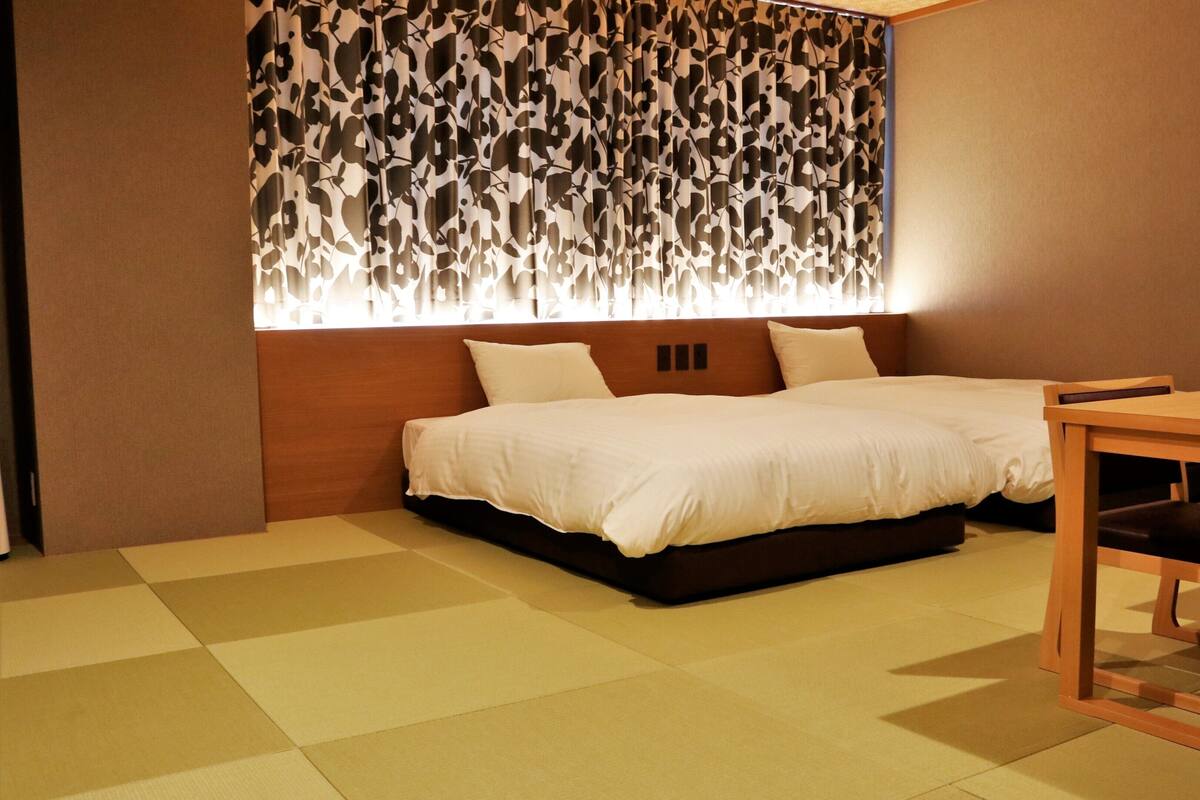 A bedroom with a bed, a wooden headboard, a dining table, and chairs.