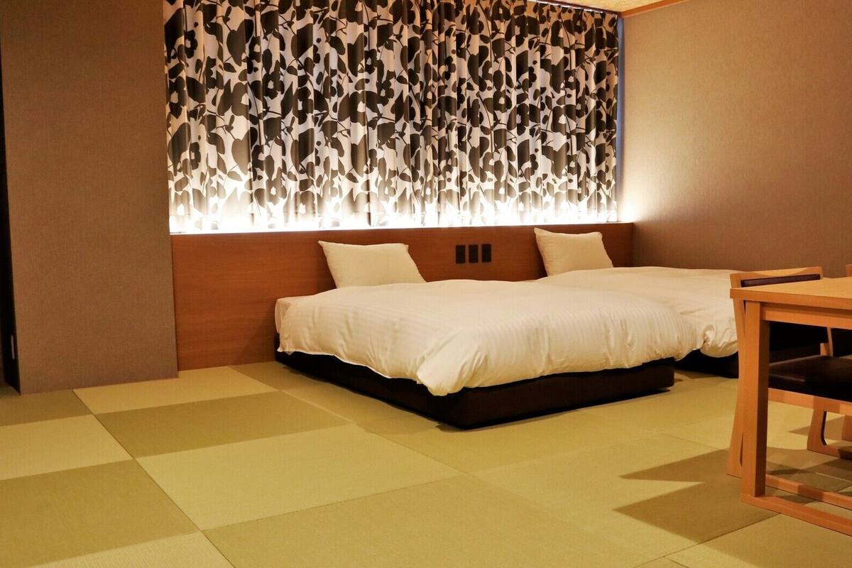 A room with a bed, a dining table, and a patterned wall.