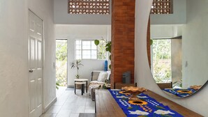 A hallway with a wooden bench, a table with a floral tablecloth, a mirror, and a door. - Cozy Apartment 810 Matamoros (Puerto Vallarta)