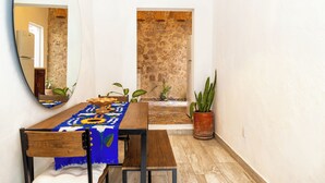 A dining area with a wooden table, chairs, and a blue tablecloth. There are potted plants and a mirror on the wall. - Cozy Apartment 810 Matamoros (Puerto Vallarta)