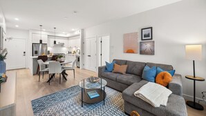 A modern living room with a grey sofa, patterned rug, and a glass coffee table. - Luxury White Rock 2BR | King Bed | Sleeps 6| Parking (Surrey)