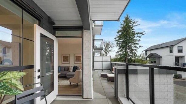 A modern apartment with a balcony, a sofa, and a dining area. - Luxury White Rock 2BR | King Bed | Sleeps 6| Parking (Surrey)