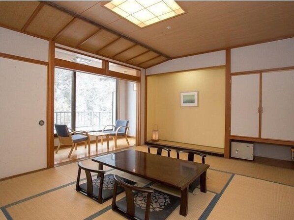 Une pièce de style japonais traditionnel, avec un sol recouvert de tatamis, une table basse avec des coussins et des portes coulissantes.