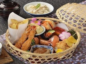 A basket of assorted Japanese food items including sushi, tempura, and other dishes, placed on a table with a floral tablecloth. - Shiobara Onsen Hotel New Momiji (Nasushiobara)