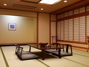 A traditional Japanese room with tatami flooring, a low table, and a sliding door. - Shiobara Onsen Hotel New Momiji (Nasushiobara)