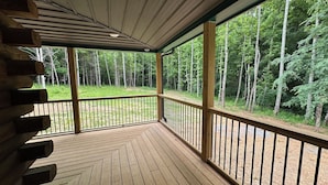 Eine Holzterrasse mit Geländer, mit Blick auf ein bewaldetes Gebiet.