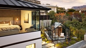 Una casa moderna con un dormitorio amplio, un patio con paredes de vidrio y vistas del paisaje circundante.