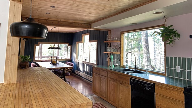 A modern kitchen with wooden cabinets, a large island, and a hanging plant. - Naked Elk Lodge: 4 Bdrms, Hot Tub, Projector TV near Mt. Rainier (Packwood)