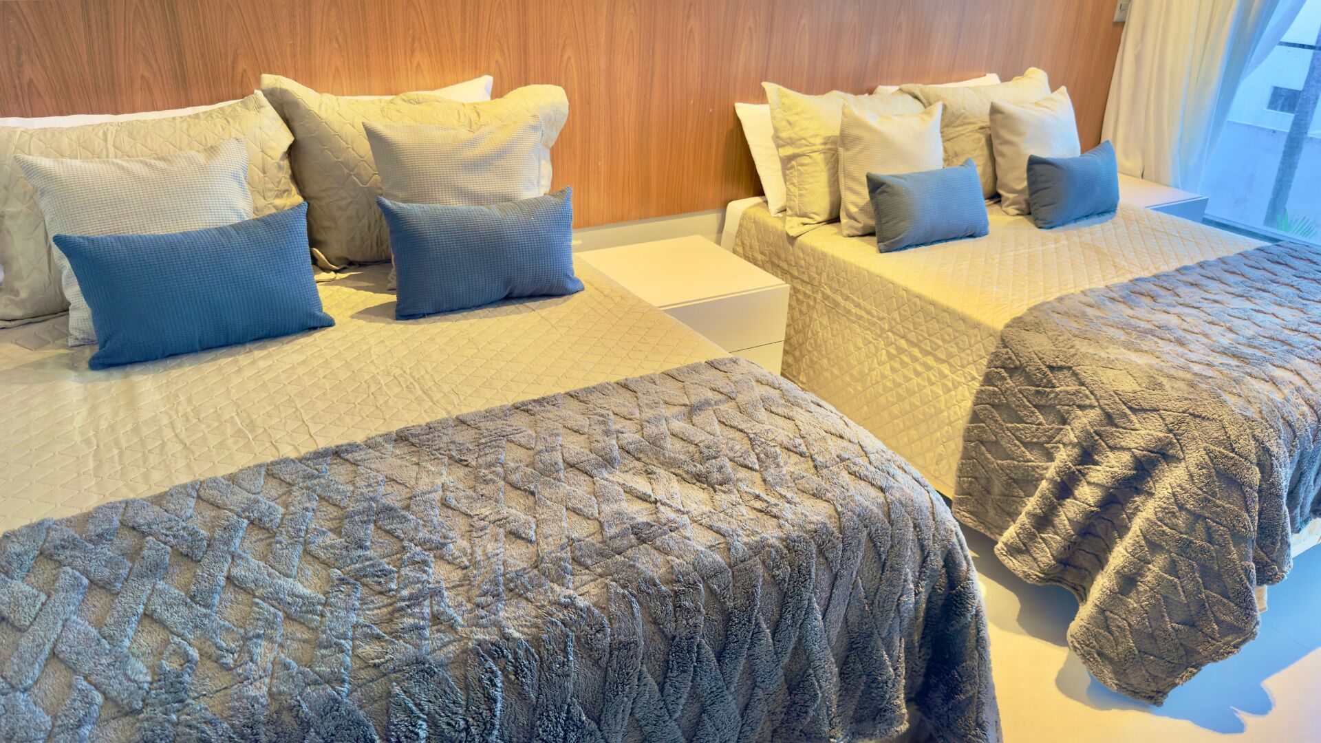 Une chambre d’hôtel avec deux lits, chacun étant agrémenté d’une courtepointe matelassée et de plusieurs oreillers.