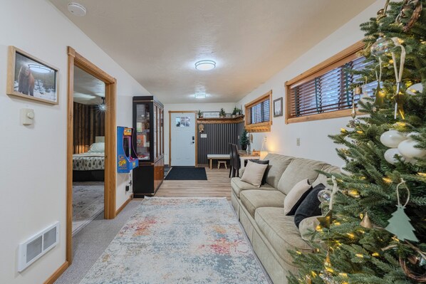 Uma sala de estar acolhedora com um sofá bege, uma árvore de Natal e um pequeno espaço de jantar.