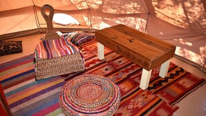 A tent interior with a wooden bench, colorful woven ottoman, and patterned rugs. - Private Eco Tent in Skiaxtro Cocoon Retreat (Marathopoli)