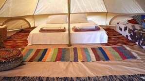 A tented accommodation room with a bed, pillows, a striped rug, and a woven basket. - Private Eco Tent in Skiaxtro Cocoon Retreat (Marathopoli)