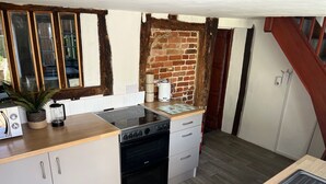 Una cocina compacta con estufa a gas, un lavamanos y una encimera de madera.