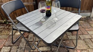 Una mesa de madera con dos sillas, una botella de vino y dos copas de vino.