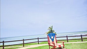 Vista de la playa con una silla roja y blanca a rayas y una palmera.