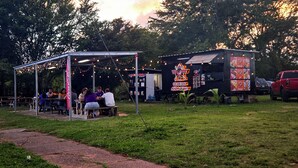 Un pabellón con luces de cuerda y mesas donde personas están cenando.