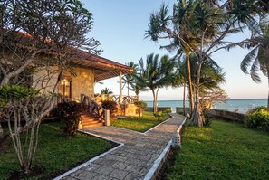 A coastal property with a paved pathway leading to a building with a tiled roof, surrounded by palm trees and a view of the sea. - Mandarin Resort Zanzibar (Kizimkazi)