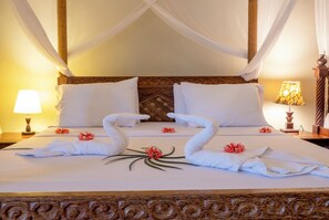 A bed with a canopy, white pillows, and towels arranged in swan shapes with flowers. - Mandarin Resort Zanzibar (Kizimkazi)