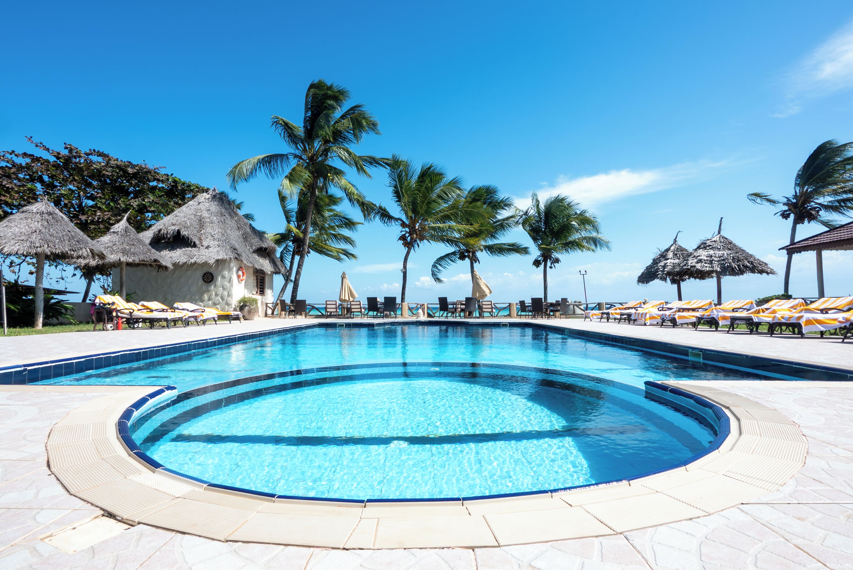 A swimming pool with lounge chairs and thatched umbrellas.