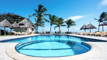A swimming pool with lounge chairs and thatched umbrellas.