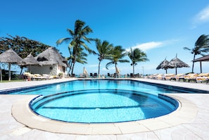 A swimming pool with lounge chairs and thatched umbrellas. - Mandarin Resort Zanzibar (Kizimkazi)