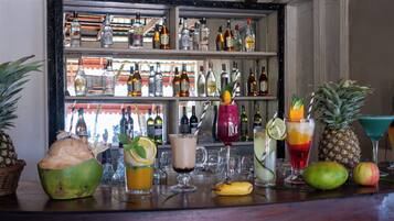 Un bar con diversas bebidas y frutas, incluyendo cocos y piñas.