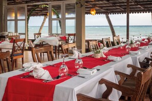 Un ristorante con tavoli apparecchiati per la cena, con vista sul mare.