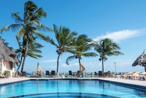 A pool area with lounge chairs, umbrellas, and palm trees. - Mandarin Resort Zanzibar (Kizimkazi)