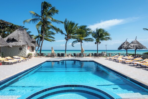 A swimming pool with lounge chairs and palm trees. - Mandarin Resort Zanzibar (Kizimkazi)
