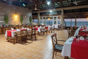 Un restaurante con mesas dispuestas para comer, una zona de bar y vistas al océano.