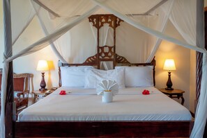 A large bed with a canopy, two bedside lamps, and a wooden headboard. - Mandarin Resort Zanzibar (Kizimkazi)