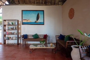 Una sala de estar con una estantería, dos sofás, una mesa de centro y un cuadro de un velero.