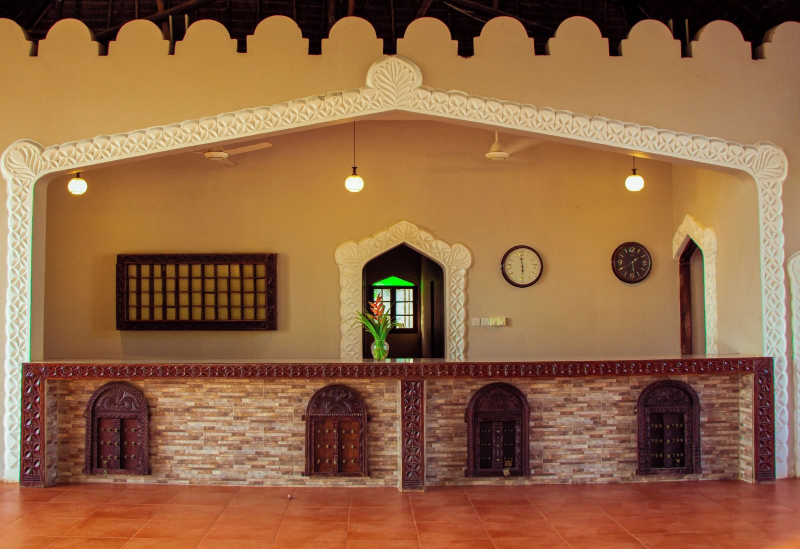 A reception area with a stone fireplace, two clocks, and a decorative archway.