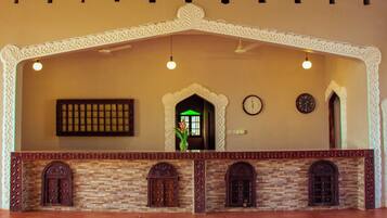 A reception area with a stone fireplace, two clocks, and a decorative archway.