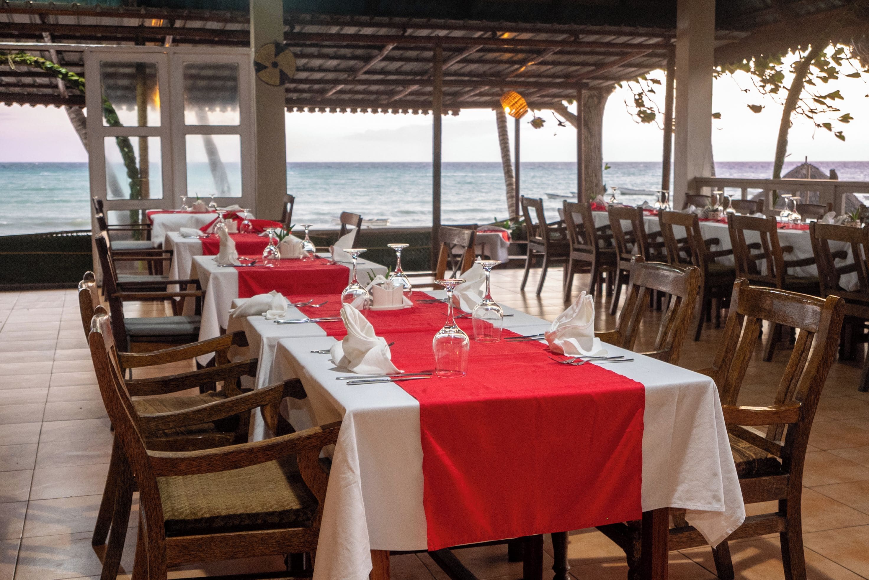 Restaurante com mesas preparadas para refeições, com vista para o oceano.