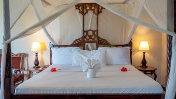 A large bed with a canopy, two bedside lamps, and a wooden headboard.