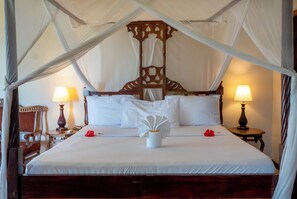 A large bed with a canopy, two bedside lamps, and a wooden headboard. - Mandarin Resort Zanzibar (Kizimkazi)