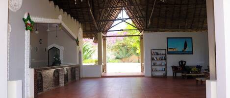A spacious room with a tiled floor, a fireplace, a bookshelf, and a painting on the wall.