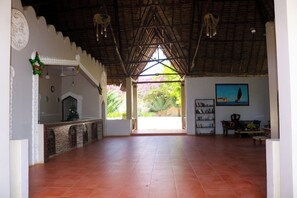 A spacious room with a tiled floor, a fireplace, a bookshelf, and a painting on the wall. - Mandarin Resort Zanzibar (Kizimkazi)
