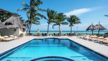A swimming pool with lounge chairs and palm trees.