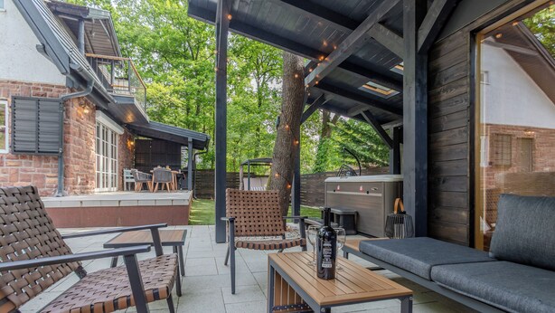 Une terrasse extérieure avec des sièges, un barbecue et un espace abrité agrémenté de guirlandes lumineuses.