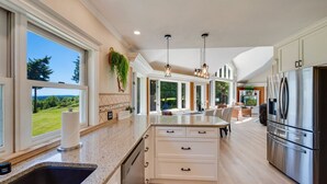 A modern kitchen with a large island, stainless steel appliances, and a view of the outdoors. - Evergreen View Retreat Sleeping up to 16 (Poulsbo)
