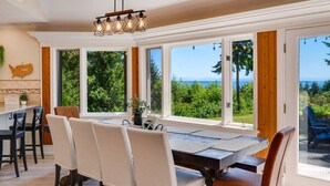 A dining area with a large table, chairs, and a view of the outdoors. - Evergreen View Retreat Sleeping up to 16 (Poulsbo)