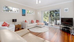A modern living room with a sectional sofa, a flat-screen TV, and a large sliding glass door leading to a patio.