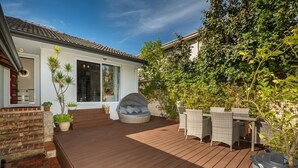 A patio with a wooden deck, outdoor seating, and potted plants.