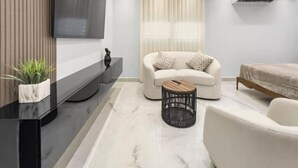 Ein modernes Wohnzimmer mit einer Couch, einem Couchtisch, einem an der Wand befestigten Fernseher und einer Decken-Klimaanlage.
