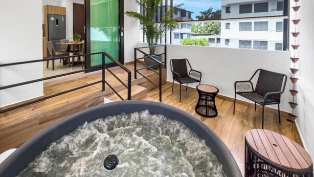 Ein moderner Poolbereich im Innenbereich mit Whirlpool, Holzboden und Sitzgelegenheiten im Freien.