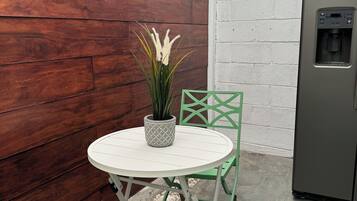 A small patio area with a round table, a potted plant, and a green chair.